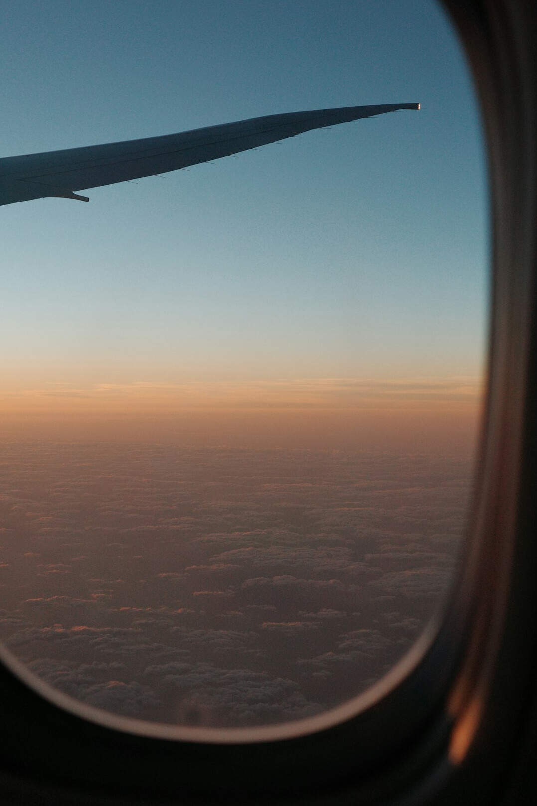 Airplane wing above the clouds at sunset